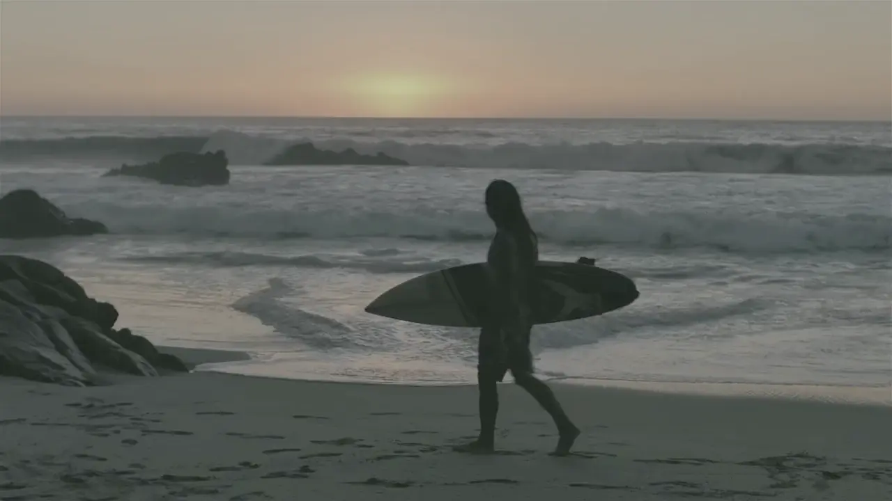 A surfer carrying a board along the shore at sunset, shown as flat grey LOG footage on the left and colour-graded on the right.