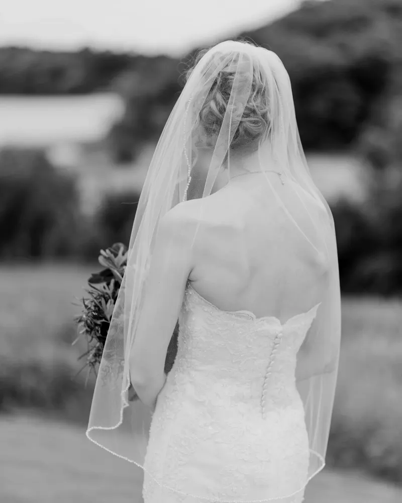 Black and white print: a bride seen from behind under her veil