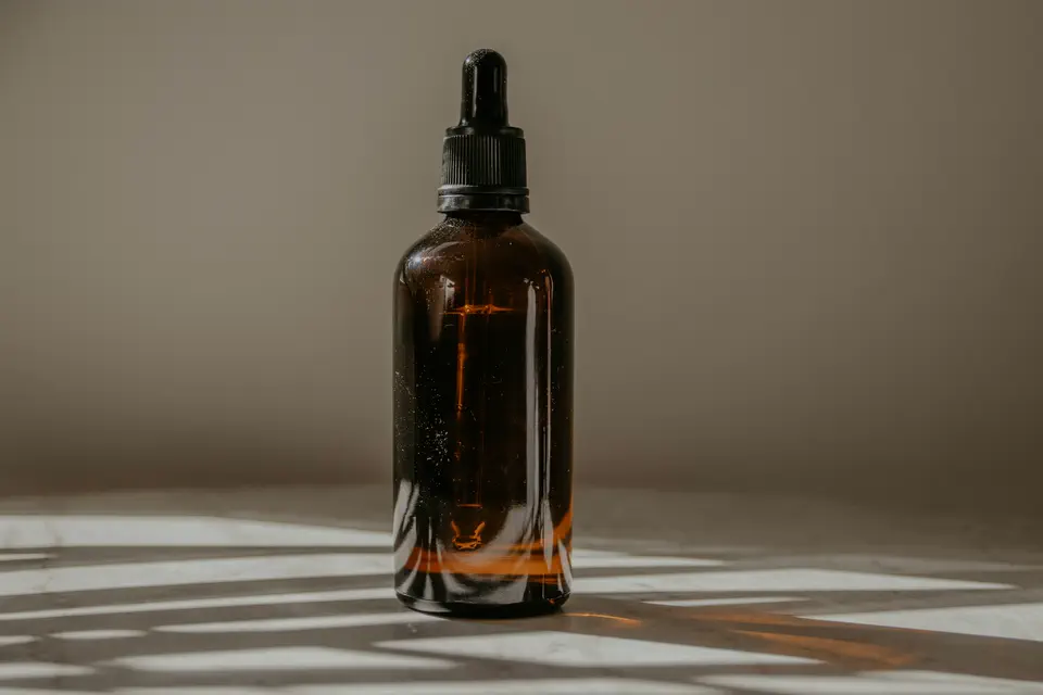 An unlabelled amber dropper bottle with window shadows falling across it