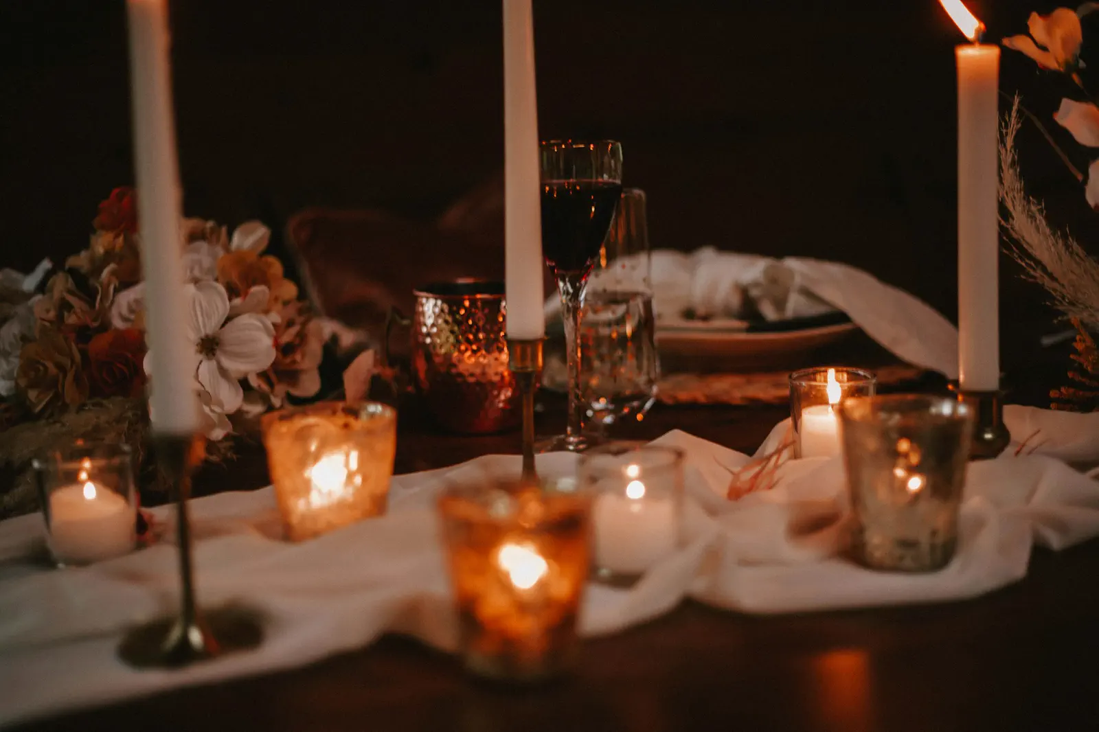 The long reception table glowing with candles and draped linen