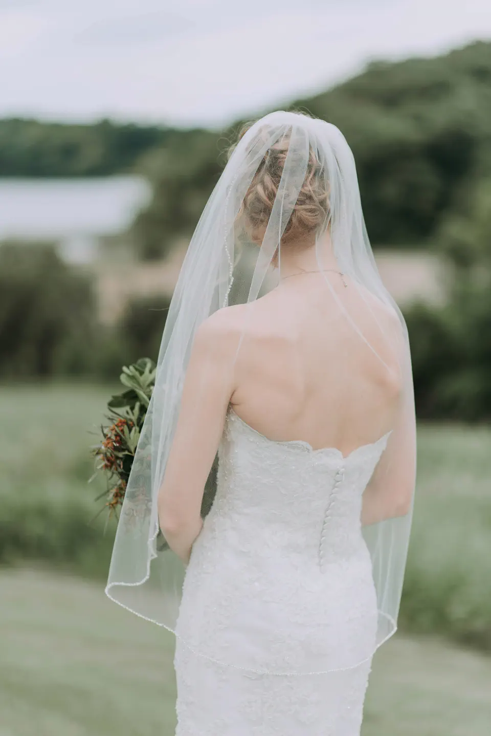 A bride seen from behind, her long veil falling over a lace gown