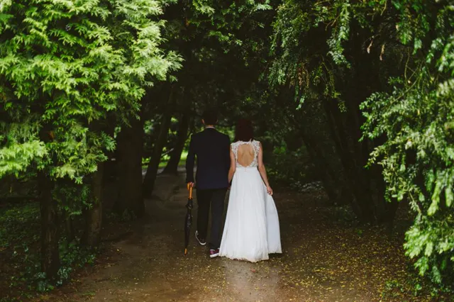 A bride and groom walking away down a leafy green garden path